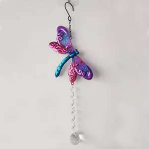 Detail view of colorful metal dragonfly garden ornament with sparkling crystal pendant.