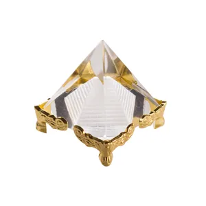 Dettaglio di una piramide in cristallo trasparente con base in metallo dorato riccamente ornata.