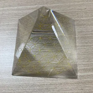 Primo piano di una piramide di cristallo con motivo fiore della vita dorato