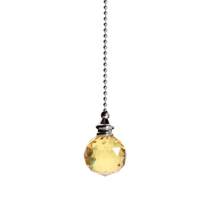 Gros plan d'un pendentif en boule de cristal jaune facetté avec une chaîne à billes argentée