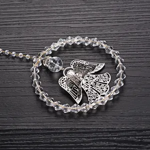 Detailed view of a crystal beaded angel pendant on a dark wood background