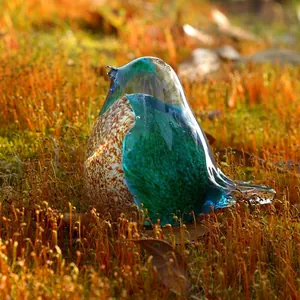 Détail d'une figurine d'oiseau en verre bleu sarcelle avec motif tacheté sur mousse