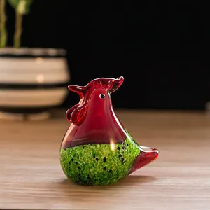 Vue détaillée d'une figurine de coq en verre rouge et vert faite à la main sur bois