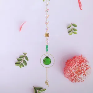 Detailopname van kristallen zonnevanger met groene prismabal en gouden bedeltjes