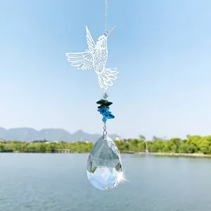 Dettaglio pendente a colibrì con prisma di cristallo appeso sopra un lago calmo
