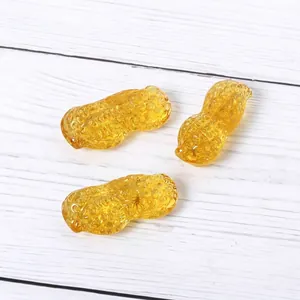 Set van drie amberkleurige glazen pinda-ornamenten op witte houten achtergrond