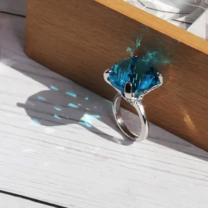 Macro view of a large blue crystal ring reflecting brilliant light patterns on wood