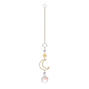 Detalle de un atrapasueños de cristal con luna, sol dorados y piedras naturales púrpuras