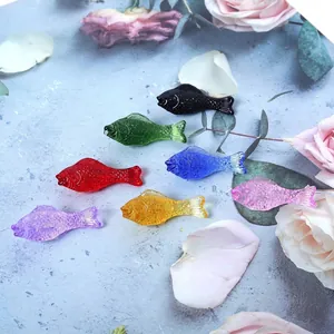 Colorful crystal fish figurines with detailed scale texture on floral stone background