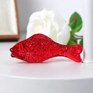 Close-up of translucent red crystal fish figurine with detailed scale texture