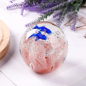 Primo piano di sfera di cristallo con delfini blu e dettagli di corallo
