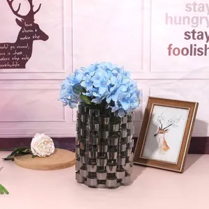 Close-up of a modern minimalist cylindrical step-patterned electroplated vase with blue flowers