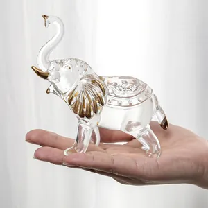 Detailed macro view of a clear crystal elephant figurine with gold accents held in hand