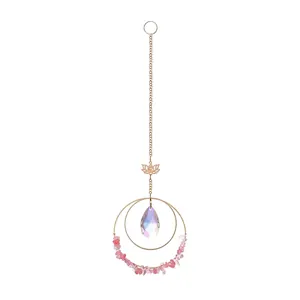 Detail showing iridescent crystal drop and lotus charm on gold hanging suncatcher.