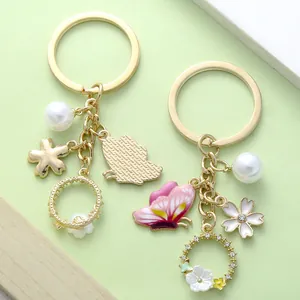 Detailed view of pink butterfly and pearl flower charms on gold-tone keychains