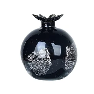 Dettaglio ravvicinato di un vaso in vetro a forma di melograno nero con decori in argento