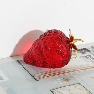 Elegante rote Erdbeerfigur aus Glas mit Goldblättern, luxuriöse Tischdekoration.