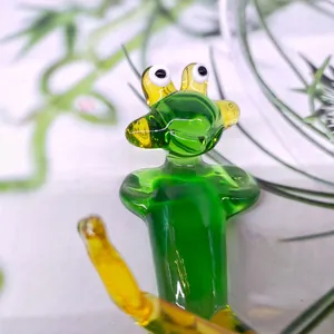 Close-up detail of a handmade green and yellow crystal glass frog in a kung fu pose