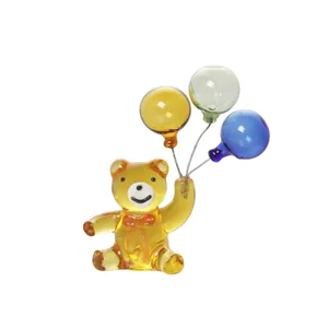 Dettaglio di una simpatica statuetta di orsetto in vetro con tre palloncini colorati.