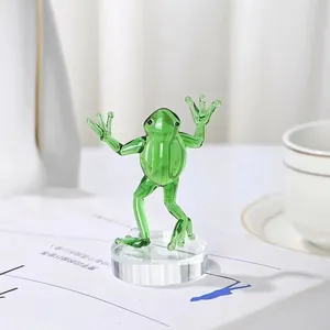 Detailed view of a green glass frog figurine standing on a clear circular crystal base