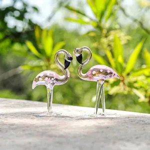 Detailopname van een paar roze kristallen flamingo-beeldjes in een tuinzetting