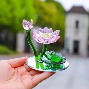 Close-up of a pink crystal lotus flower ornament with a small green frog on a leaf