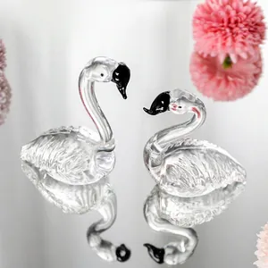 Detailopname van een paar heldere kristallen flamingofiguren op een spiegelend vlak
