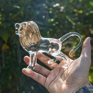 Close-up of a crystal glass lion figurine with golden mane held in hand for scale