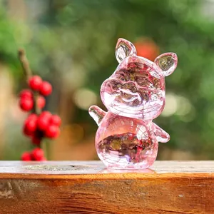 Primo piano di una graziosa statuina di maiale in cristallo rosa su superficie in legno