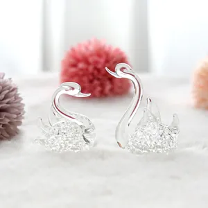 Close-up of elegant clear crystal swan figurines with a textured base on a soft surface