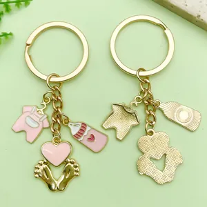 Cartoon baby-themed gold keychains with pink enamel bottle onesie and feet charms