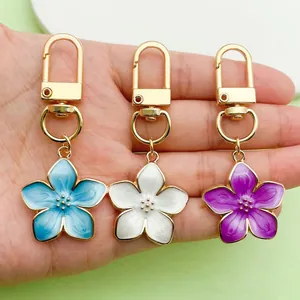 Close-up detail of three pearlescent enamel flower keychains with gold-toned metal clips