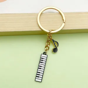 Close-up of musical keychain featuring piano keys and eighth note charms on gold ring.