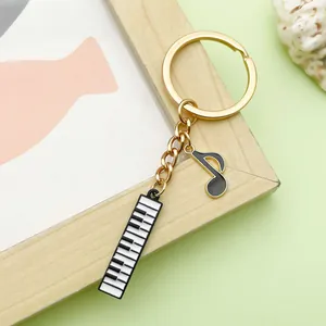 Detail view of the piano keyboard and musical note charms on a polished gold keychain