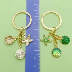 Detail view showing measurements of green mermaid scale and starfish charms on gold keychain
