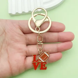 Primer plano detallado de un llavero de metal dorado con un dije love y un fútbol.