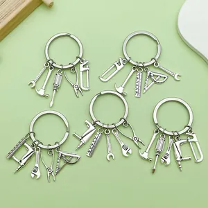 Close-up of five silver tool-themed keychains with hammer, saw, and drill charms.