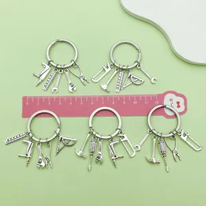 Macro view of silver tool-themed keychains featuring a saw, hammer, and wrench pendant.