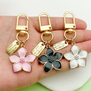 Close-up of pearlized cherry blossom keychains with gold finish in pink, black, and white