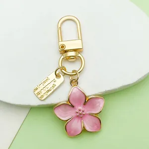 Close-up of a pink enamel cherry blossom keychain with gold-plated metal hardware