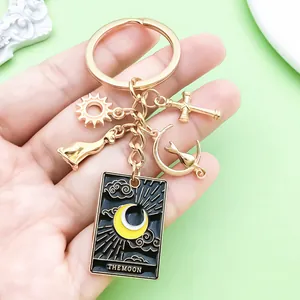 Detailed view of The Moon Tarot card keychain with black enamel and golden alloy charms.