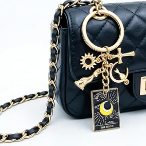 Close-up detail of gold-plated tarot keychain with sun and moon charms on black quilted bag