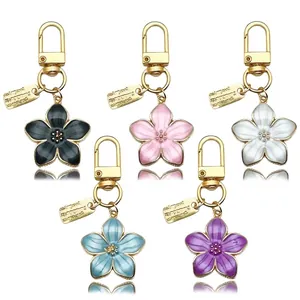 Detalle de llaveros con flor de cinco pétalos en negro, rosa, blanco, azul y morado.