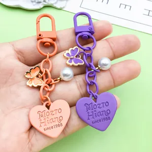 Detail view of heart-shaped keychains with butterfly and pearl charms in orange and purple.