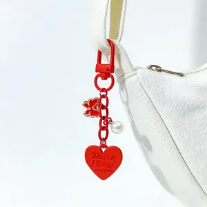 Detailed close-up of a red zinc alloy heart and butterfly keychain on a white bag