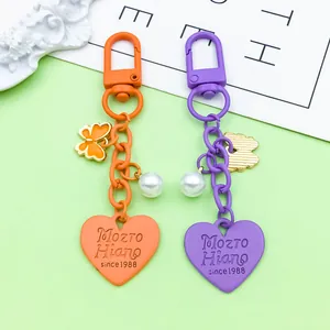 Close-up of heart-shaped zinc alloy keychains with butterfly and pearl charms.