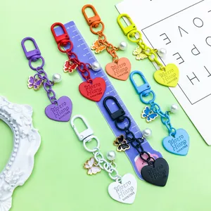 Close-up view of seven colorful heart-shaped keychains with butterfly charms and pearls