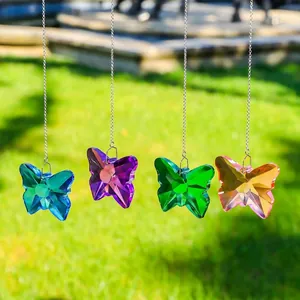 Attrape-soleil papillon en cristal coloré suspendu à des chaînes dans un jardin