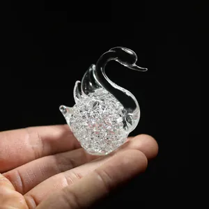 Close-up of a decorative crystal swan figurine with bubble texture held in hand