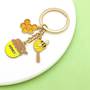 Gros plan de jolis breloques abeille et pot de miel sur un porte-clés doré tendance